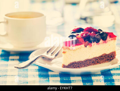 Effet Retro Vintage style hipster filtré de l'image fruits dessert gâteau au fromage sur la plaque avec la fourche et la tasse de café sur bleu checker Banque D'Images