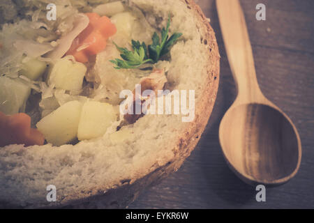 Style rétro photo de la soupe aux choux polonais traditionnels dans une miche de pain Banque D'Images