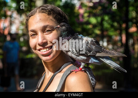 New York, NY - 31 juillet 2015 - Woman walking through Washington Square Park avec friendly pigeons sur chaque épaule. Le 22 juillet 200 à 300 des parcs de pigeons ont été portés disparus. Banque D'Images