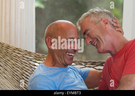 Homme couple gay senior en vacances étant affectueux en hamac au bed and breakfast Banque D'Images