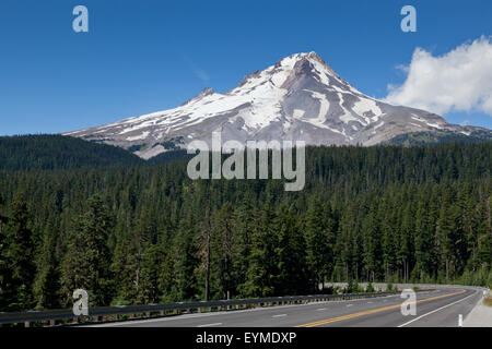 Le pic enneigé du Mont Hood dans l'Oregon s'élevant au-dessus d'une forêt luxuriante avec une route qui vide dans les arbres. Banque D'Images