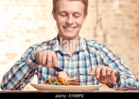 Handsome man eating salad in cafe Banque D'Images