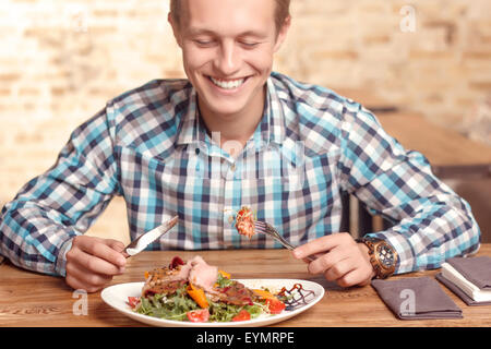 Handsome man eating salad in cafe Banque D'Images