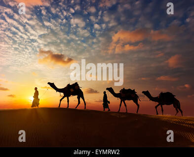 Arrière-plan de voyage Rajasthan - deux chameliers indiennes (chameliers) avec des chameaux silhouettes dans les dunes du désert de Thar au coucher du soleil Banque D'Images