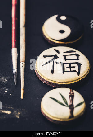 Les cookies à la main avec des caractères chinois 'fortune', bambou et Yin Yang. Focus sélectif. Banque D'Images