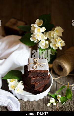 Mascarpone au chocolat brownies sont empilés avec des fleurs sur table en bois Banque D'Images