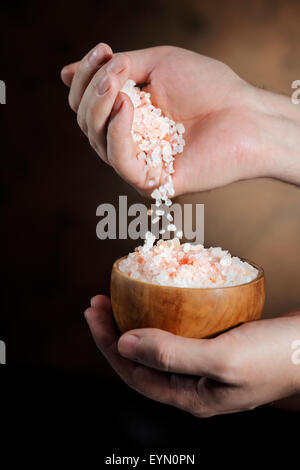 Les cristaux de sel de l'himalaya verser l'homme de sa main. Banque D'Images