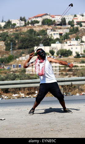 Un jeune Palestinien jette une pierre vers des soldats israéliens dans le camp de réfugiés de Jalazone lors d'affrontements en Cisjordanie. Affrontements entre jeunes Palestiniens et forces israéliennes ont éclaté dans le camp de réfugiés de Jalazone en Cisjordanie, près de Ramallah, après 48 heures d'intenses la violence en Cisjordanie. Le 31 juillet les colons israéliens juifs ont mené une attaque terroriste, l'incendie d'une maison près de Naplouse en village de la Douma, où un bébé de 18 mois, Ali Saad, Dawabsha a été brûlé vif. D'autres membres de la famille, y compris son frère aîné sont toujours dans un état critique. Le même jour, 17-year-old Laith al-Khaldi Banque D'Images