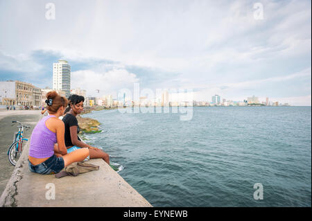 La HAVANE, CUBA - Mai 2011 : Les Cubains vous détendre sur le mur de la jetée, un endroit populaire pour les activités sociales, contre la ville. Banque D'Images