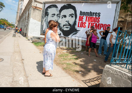 La HAVANE, CUBA - Juin 2011 : Les Cubains s'aligner devant un panneau de propagande avec les chefs révolutionnaires. Banque D'Images