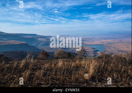 Tôt le matin, view of dry herbes brûlées et la vallée en paysage d'hiver avec de l'eau dans le barrage de stockage dans les montagnes de Drakensberg South Af Banque D'Images