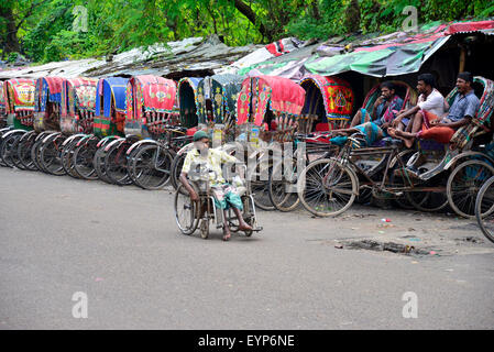 Les conducteurs de pousse-pousse du Bangladesh attendent des passagers à côté d'un fauteuil roulant avec va désactiver à Dhaka. Le Bangladesh. En juillet 2015, des milliers de personnes du pays migrent vers la capitale Dhaka pour travailler comme conducteur de pousse-pousse comme ils n'ont pas de travail dans les villages pendant les trois à six mois en période de mousson. Les conducteurs de pousse-pousse chaque gagnent souvent moins de 4 dollars par jour. Banque D'Images