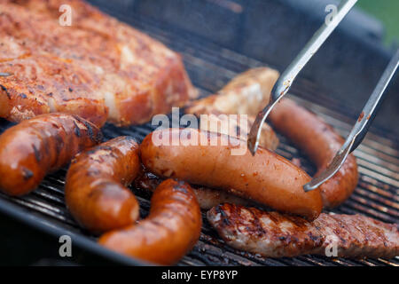 Un assortiment de viandes de poulet et de porc et saucisses sur le gril du barbecue Banque D'Images