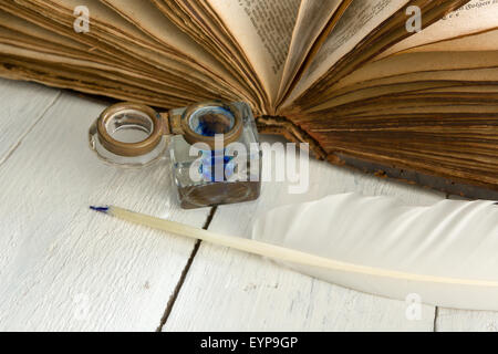 Feather quill, pot d'encre bleu et médiévale livre sur un tableau peint blanc rustique Banque D'Images