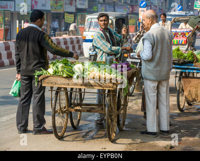 L'homme bien habillé avec un pantalon froissé parfaitement à un panier de légumes dans la rue dans la ville sainte de Varanasi, Inde Banque D'Images