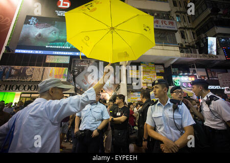 Hong Kong, Hong Kong. 09Th Aug 2015. Un pro de la démocratie protestataire est titulaire d'un parapluie jaune en face de la police. Parapluie jaune devient un symbole de la démocratie depuis le mouvement de coordination a eu lieu à Hong Kong l'année dernière. La force de la police a été déployée pour protéger les artistes de rue Beijing Pro sur leur réunion avec le pro de la démocratie des manifestants dans le quartier commercial de Mong Kok. © Geovien Si/Pacific Press/Alamy Live News Banque D'Images