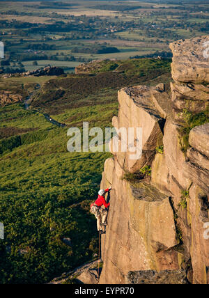 Un grimpeur de grimper sur les rochers de Ilkley Ilkley moor Banque D'Images