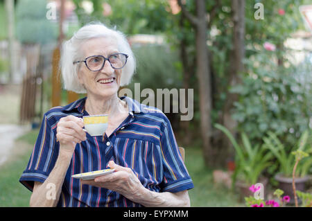 Vieille grand-mère ayant tasse de café en plein air Banque D'Images