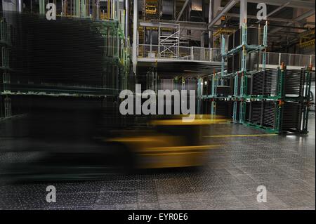 À l'intérieur d'une usine de voitures modernes, des véhicules et des pièces se déplacent à travers le processus de production, d'un chariot élévateur, brouille par warehouse Banque D'Images