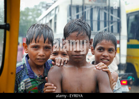 Portrait d'enfants jouant sous la pluie sur une route très fréquentée pendant les jours de pluie à Uttar Pradesh, Inde. Banque D'Images