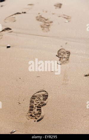 Empreintes de pieds dans le sable sur une plage. Banque D'Images