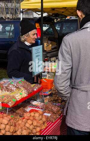 Une vieille femme vendant des écrous sur un marché agricole local. Banque D'Images