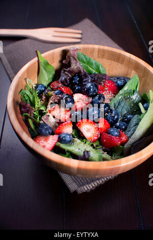 Salade de fruits frais sur bol en bois avec des baies et d'épinards Banque D'Images
