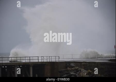 Pays de Galles Aberystwyth UK, le mardi 04 août 2015 UK weather : les pauvres de l'été continue en tant que force de coup de vent 6 et d'une moissonneuse-batteuse avance à marée haute, les vagues s'écraser sur la promenade à Aberystwyth, sur la côte ouest du pays de Galles au Royaume-Uni. Le Met Office a lancé un avertissement, alors que le système à basse pression à l'ouest de la France est à l'origine de grosses vagues qui touchent les régions de l'ouest à travers la journée. La Royal National Lifeboat Institution (RNLI), incite les gens à prendre soin comme ils visitent les côtes sur leurs vacances d'été. Crédit photo : Keith Morris/Alamy Live News Banque D'Images