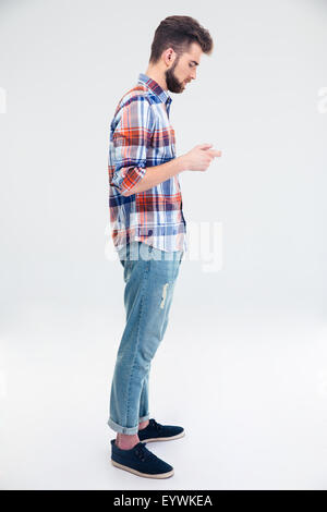 Side view portrait of a young man using smartphone isolé sur fond blanc Banque D'Images