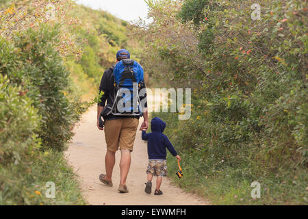 Vue arrière d'un homme qui marche avec son fils Banque D'Images