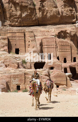 L'homme local avec des chameaux, des tombes dans la région de Wadi Musa en arrière-plan, Petra, Site du patrimoine mondial de l'UNESCO, la Jordanie, Moyen-Orient Banque D'Images