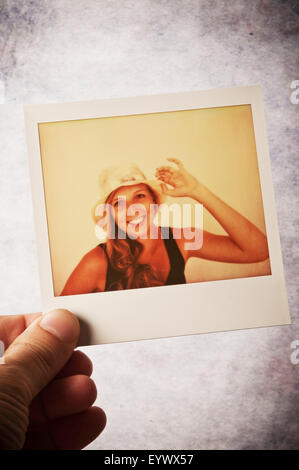 Homme main tenant une photo d'un Polaroid girl smiling with hat Banque D'Images