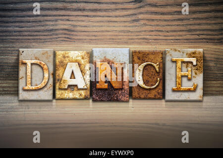 Le mot 'dance' écrit en métal rouillé type letterpress assis sur un rebord en bois, arrière-plan. Banque D'Images