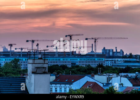 Berlin vue du coucher de soleil sur le toit de l'immeuble. Grues, bâtiments et coucher de soleil d'or. Banque D'Images