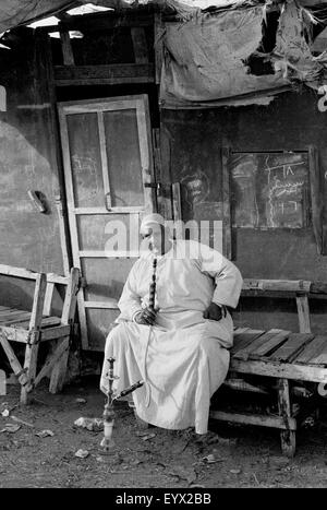 Homme qui fume la chicha à Birqash marché aux chameaux brian mcguire Banque D'Images