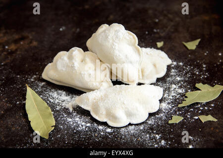 Pâtisserie brutes quenelles avec les feuilles de laurier close up sur pan noir Banque D'Images