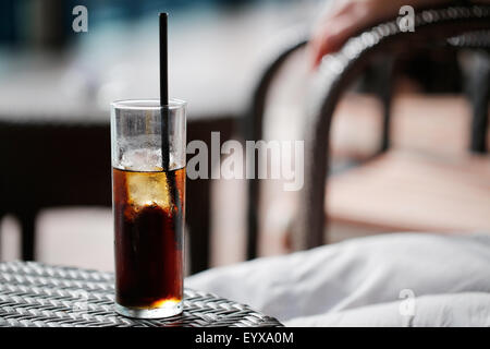 Un grand verre de coca, avec de la glace, sur une table. la boisson est refroidie et le verre condensated en conséquence. servi avec une paille à boire avec. Banque D'Images