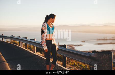 Piscine shot of young woman standing on country road à à une vue. Caucasian woman on marche matinale. Banque D'Images