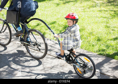 Boy riding tandem avec businessman père à sunny park Banque D'Images