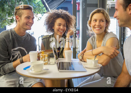 Friends hanging out with laptop and coffee sur patio cafe Banque D'Images
