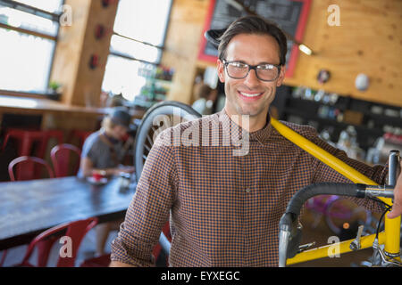 Portrait of smiling man with eyeglasses transportant location in cafe Banque D'Images