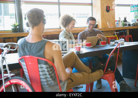 Les gens à l'aide de digital tablets in cafe Banque D'Images