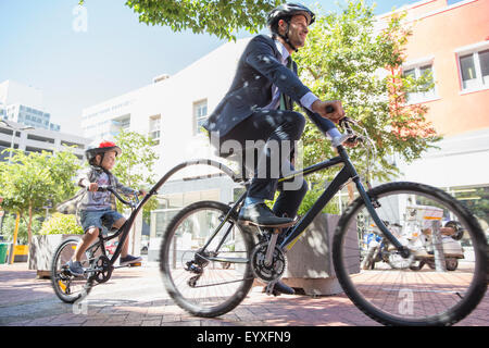 Businessman père en fonction de circonscription tandem avec fils sur trottoir urbain Banque D'Images