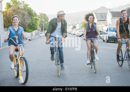 Friends riding bicycles in a row on street Banque D'Images