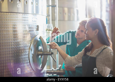 Vin blanc vignerons examinant à tva en acier inoxydable dans la cave de vinification Banque D'Images