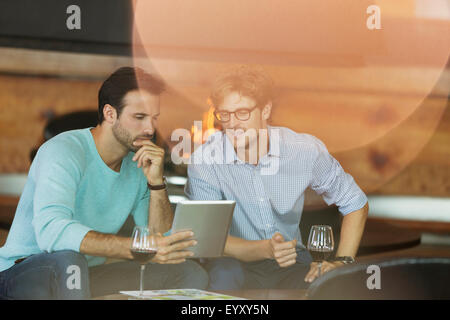 Les hommes de boire du vin rouge et using digital tablet Banque D'Images