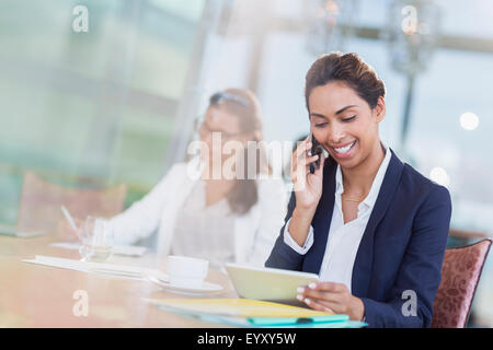 Businesswoman talking on cell phone and using digital tablet in office Banque D'Images