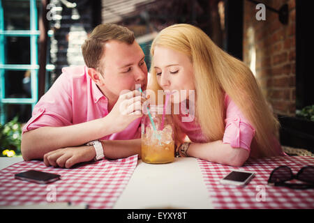 Cheerful couple surfez sur le web, à la recherche d'une photo sur smartphone, café en plein air d'été Banque D'Images