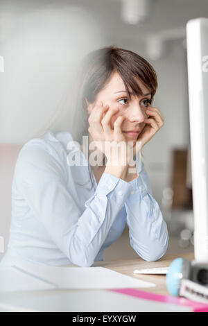 Frustrés brunette businesswoman working at computer in office Banque D'Images