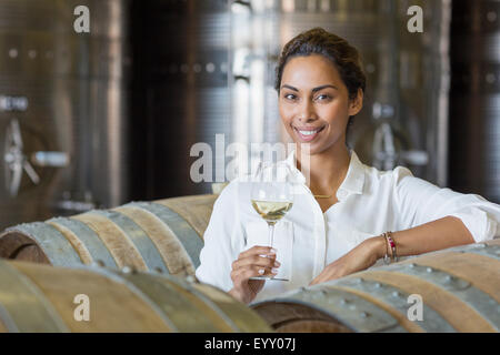 Portrait confiant vigneron boire le vin blanc dans la cave de vinification Banque D'Images